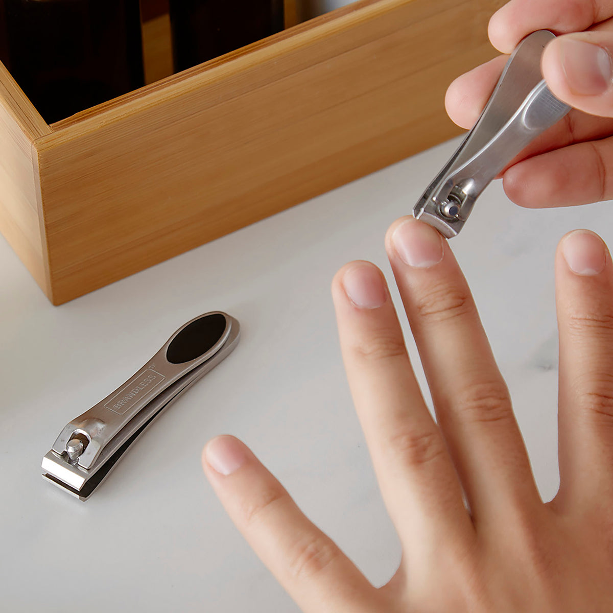 Woman demonstrates the use of the fingernail clipper on her left hand