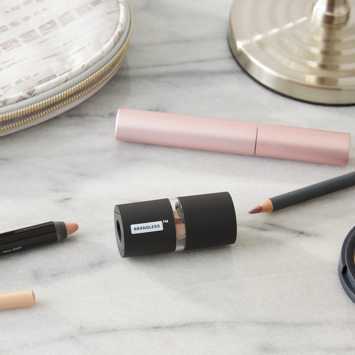 Lifestyle photo, showing the brandless dual sharpener next to various sized beauty pencils that are all compatible, sitting on a bathroom counter.