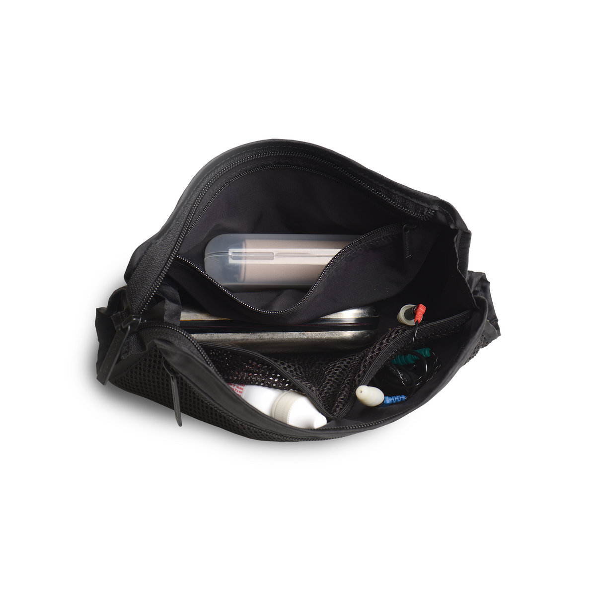 Lifestyle. Top down view of a loaded travel organizer unzipped and splayed open to show the case holding and organizing glasses cases, eye drops, ear plugs, headphones, and misc easily in separate internal compartments.