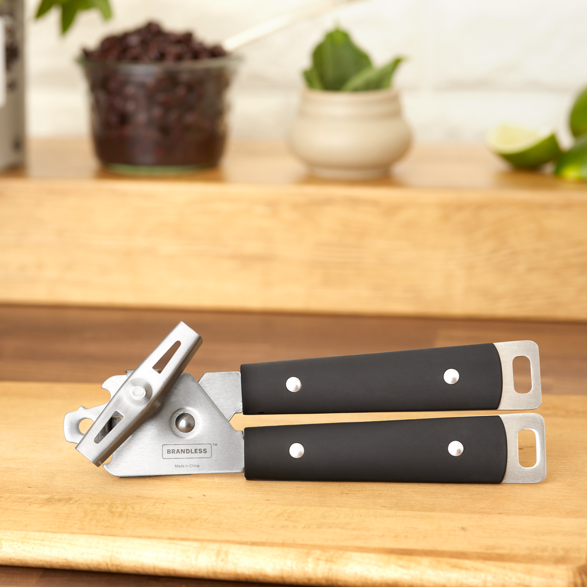 Lifestyle photo, can opener side view sitting on a wood cutting board.