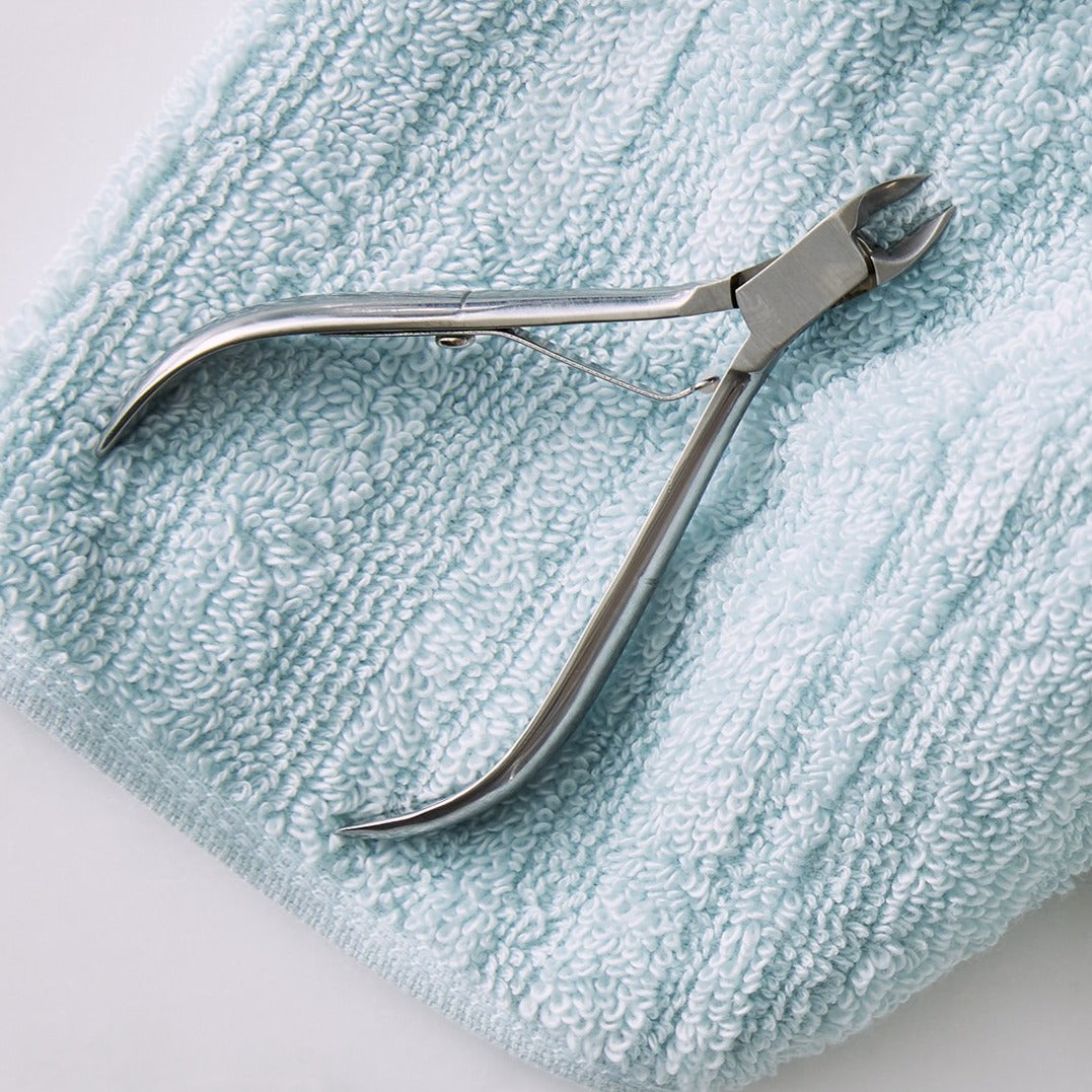 Cuticle nippers laying on a light blue towel.
