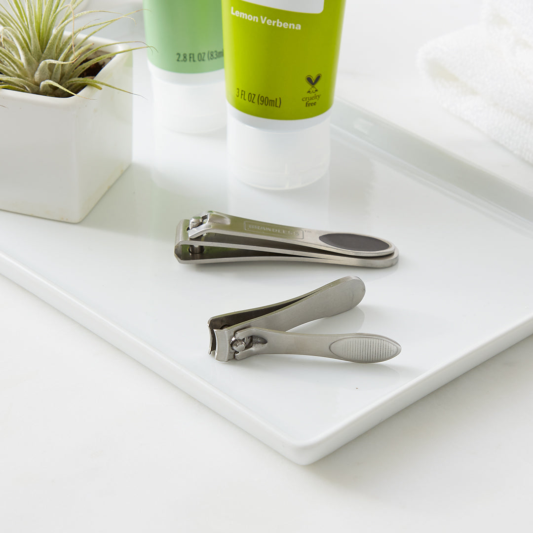 Lifestyle  photo. Nail clipper set sits in a bathroom organizer tray next to a little succulent in a tiny white square pot and lemon verbena hand cream.