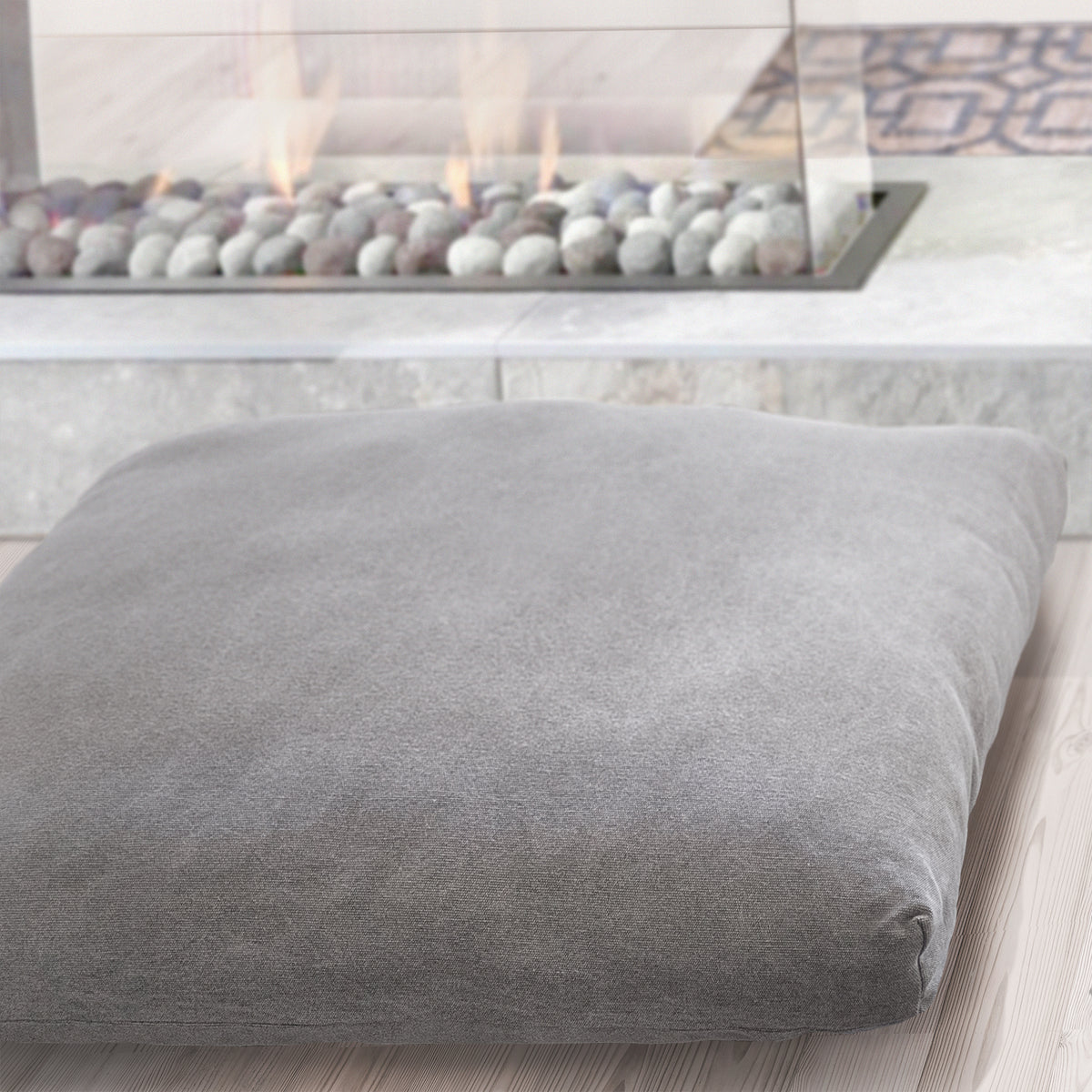 Lifestyle photo. Floor cushion on a wood floor in front of a fireplace.