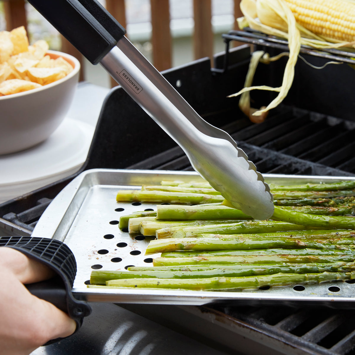Lifestyle photo, chef servs roasted asparagus spears directly from a medium grill top tray.