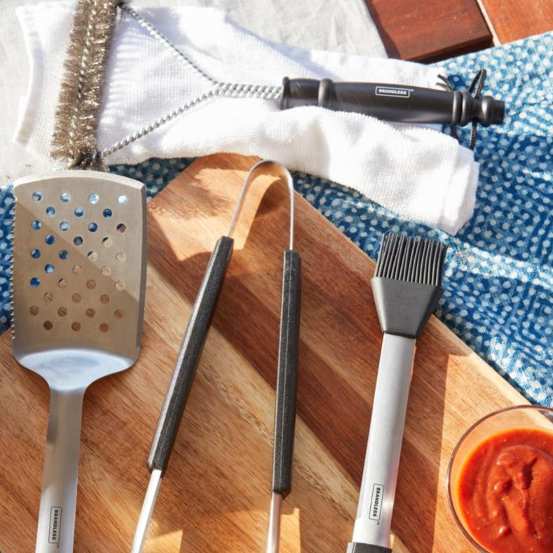 Product collage, grill basting brush, spatula, tongs, and cleaning brush arrayed on a table.
